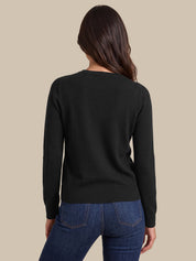 A woman shown from the back wearing a black long-sleeve knit sweater and blue jeans against a plain beige studio background.