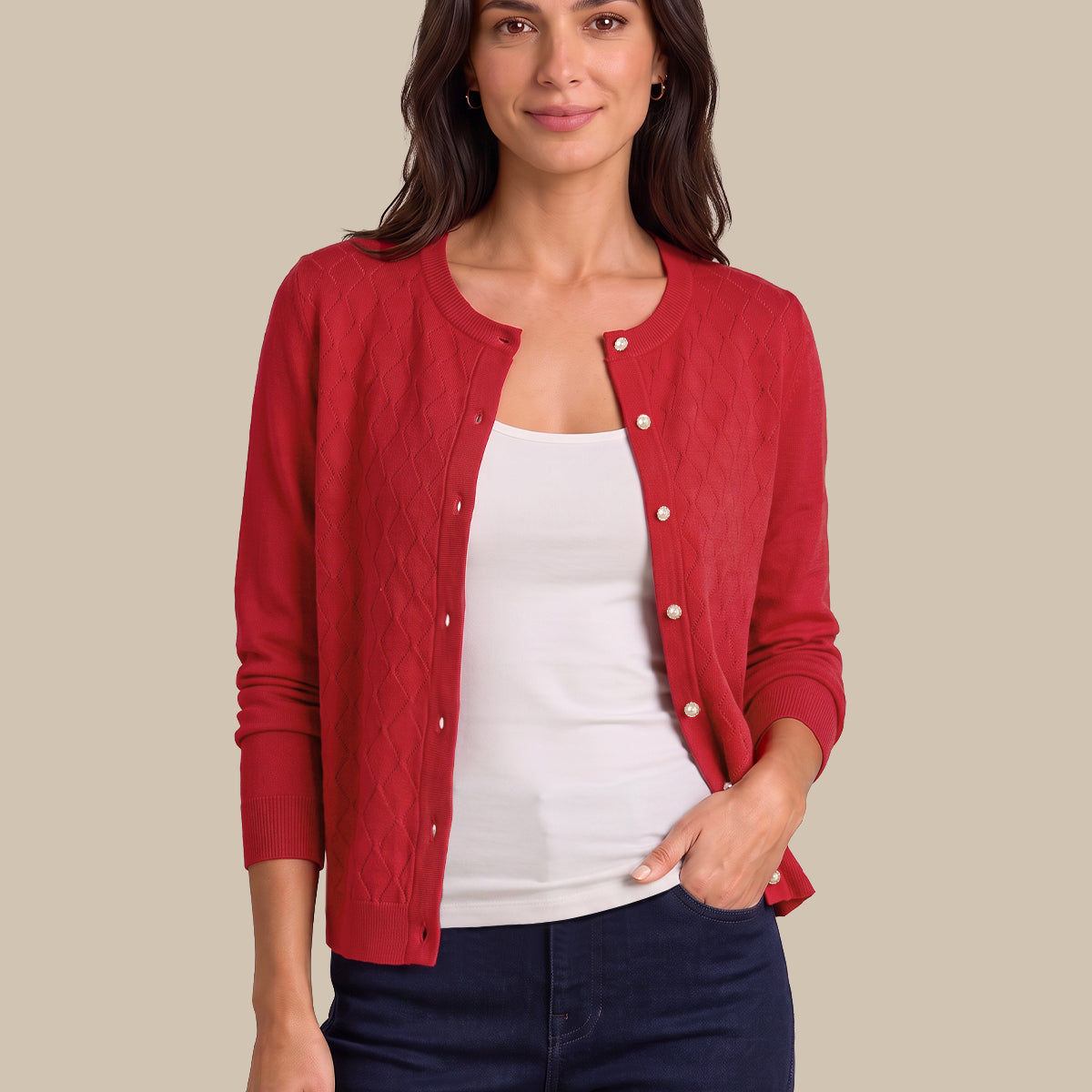 A woman modeling a red button-front cardigan over a white tank top and dark navy jeans, standing against a plain beige studio background.