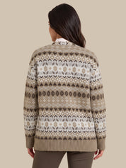 A woman viewed from the back wearing a beige and white Fair Isle patterned knit sweater, paired with brown pants, against a solid beige background.