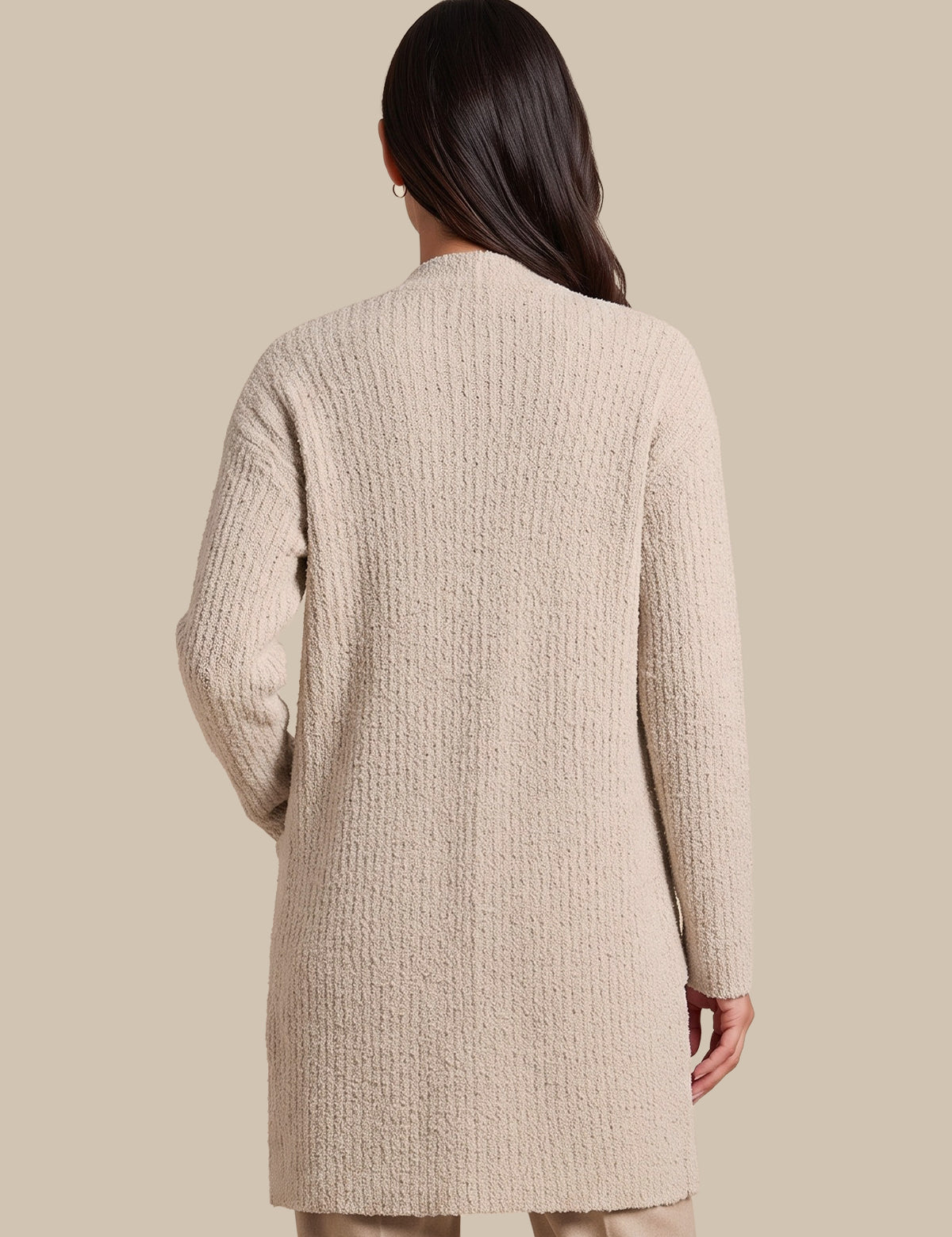 A woman shown from the back wearing a textured, long-sleeve knit cardigan in a light beige color, set against a solid beige studio background.