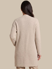 A woman shown from the back wearing a textured, long-sleeve knit cardigan in a light beige color, set against a solid beige studio background.
