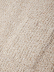 A close-up texture shot of a plush, looped pile fabric in a warm cream or light beige color.