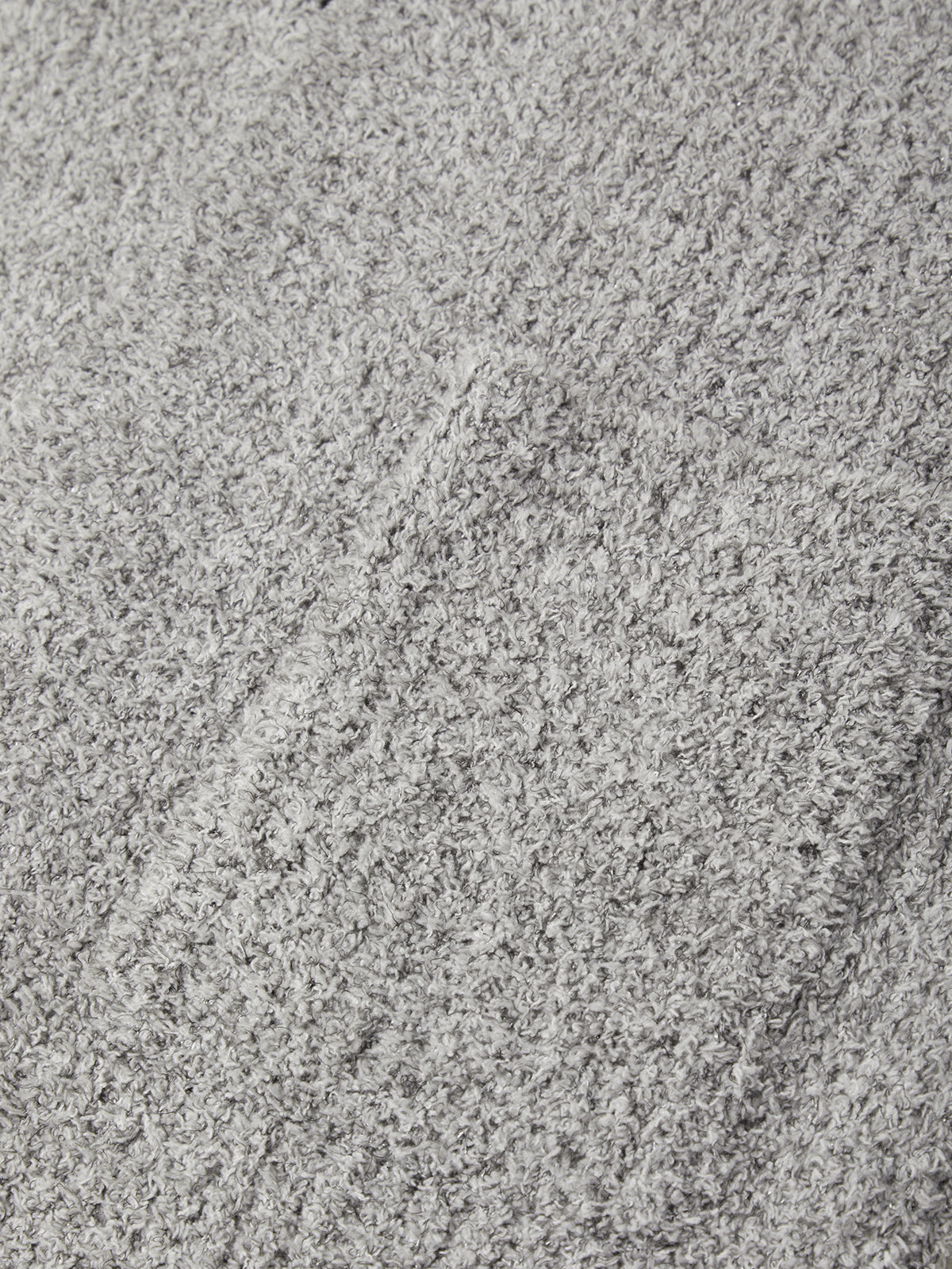 A close-up texture shot of a light gray plush or bouclé fabric surface with subtle tonal variation.