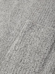 A close-up texture shot of a light gray plush or bouclé fabric surface with subtle tonal variation.