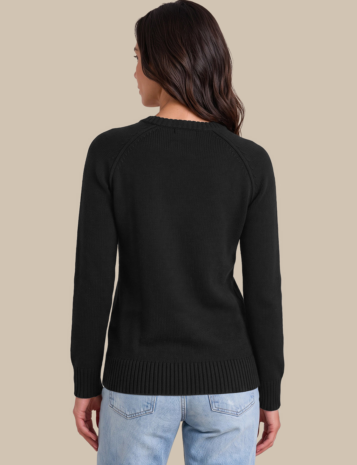 A woman shown from the back wearing a black long-sleeve knit sweater and light blue jeans, standing against a solid beige studio background.