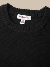 Close-up of a black knit sweater with a ribbed crew neck, showing the inside neck label which reads '89° Maison'.