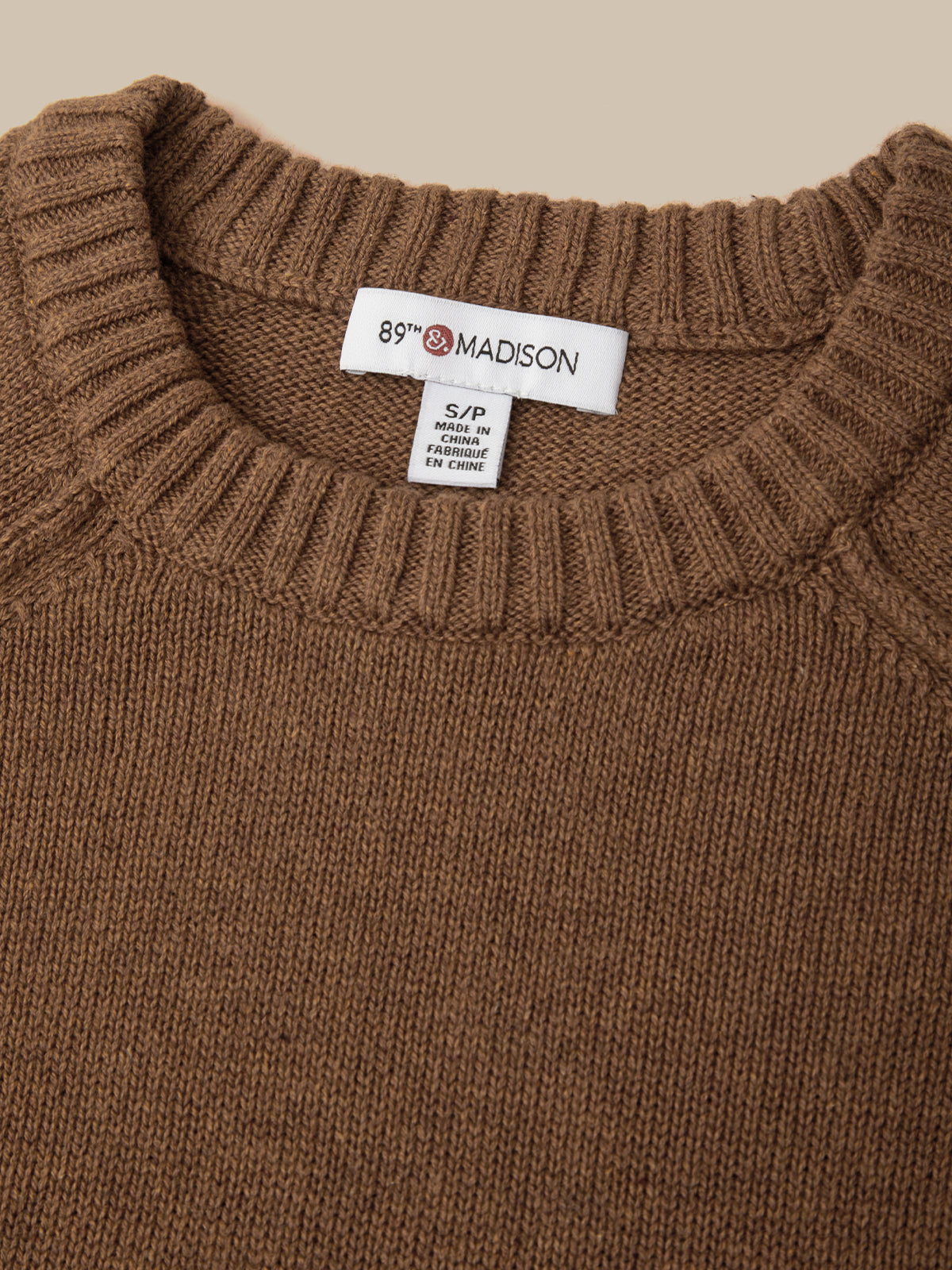 Close-up of a brown ribbed-knit sweater neck with a white interior label reading 89th Madison.