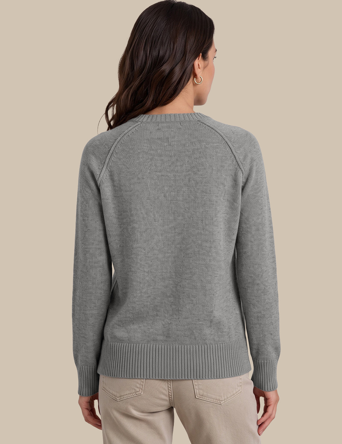 A woman shown from the back wearing a heather gray knit sweater and light beige pants against a solid beige background.