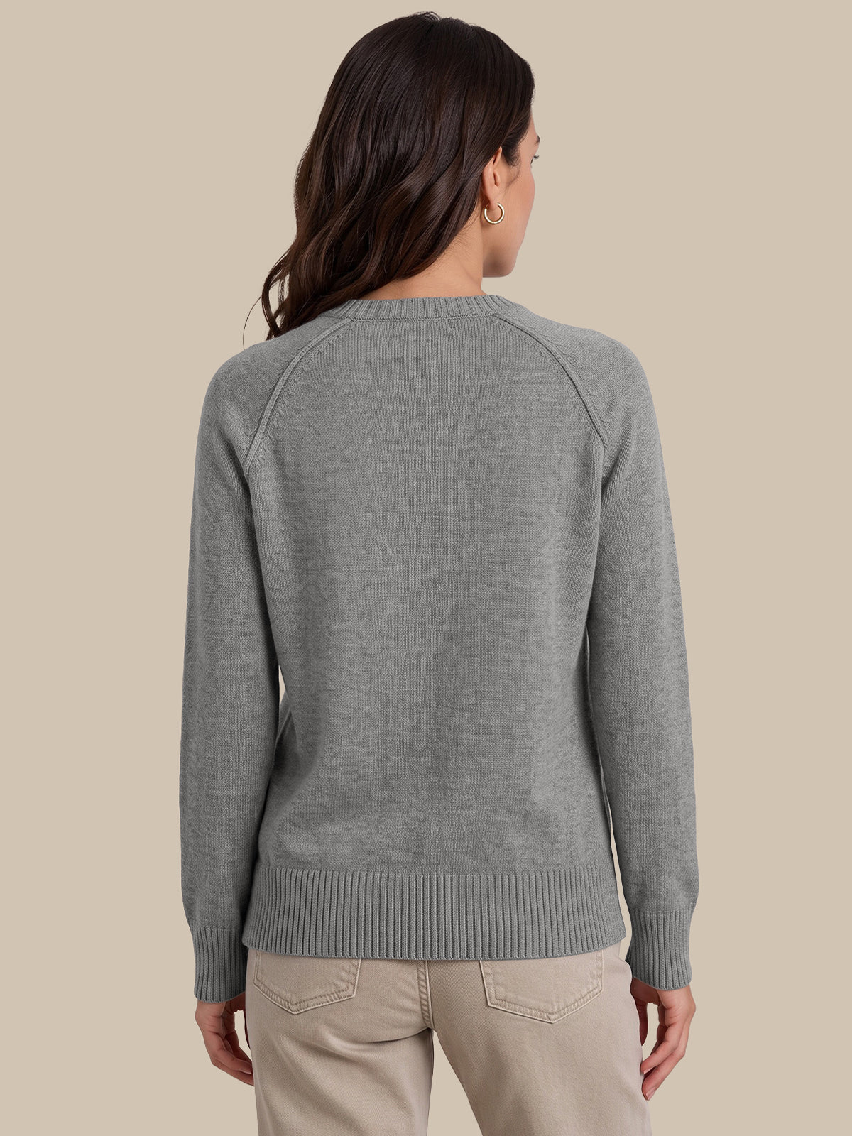 A woman shown from the back wearing a heather gray knit sweater and light beige pants against a solid beige background.