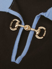 Close-up of a black knit garment featuring a light blue ribbed trim and a prominent gold horsebit hardware detail.