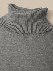 Close-up of a gray ribbed knit turtleneck sweater against a solid beige background.