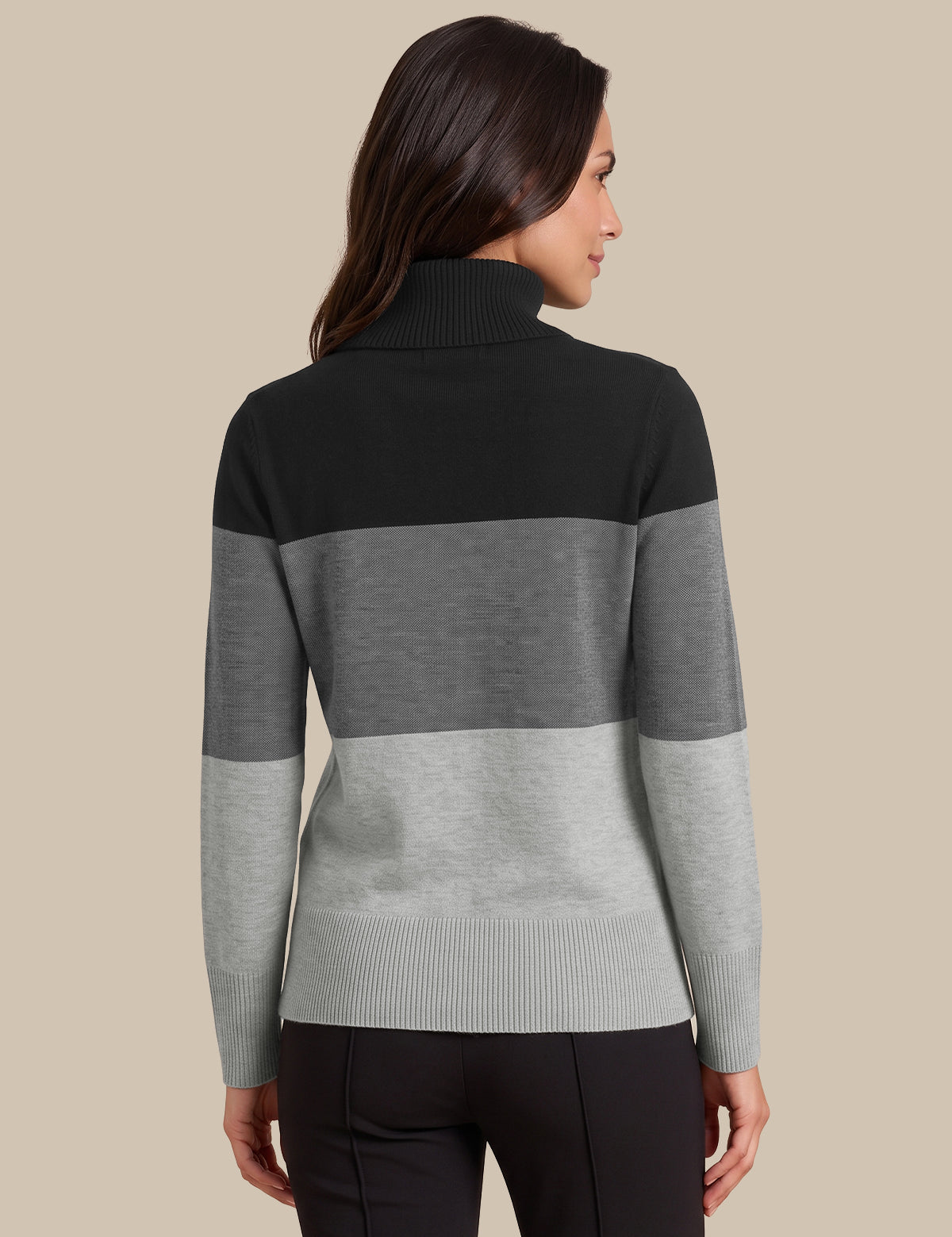 A woman shown from the back wearing a color-blocked knit mock-neck sweater with horizontal stripes in black, medium gray, and light gray, paired with black pants, against a solid beige background.