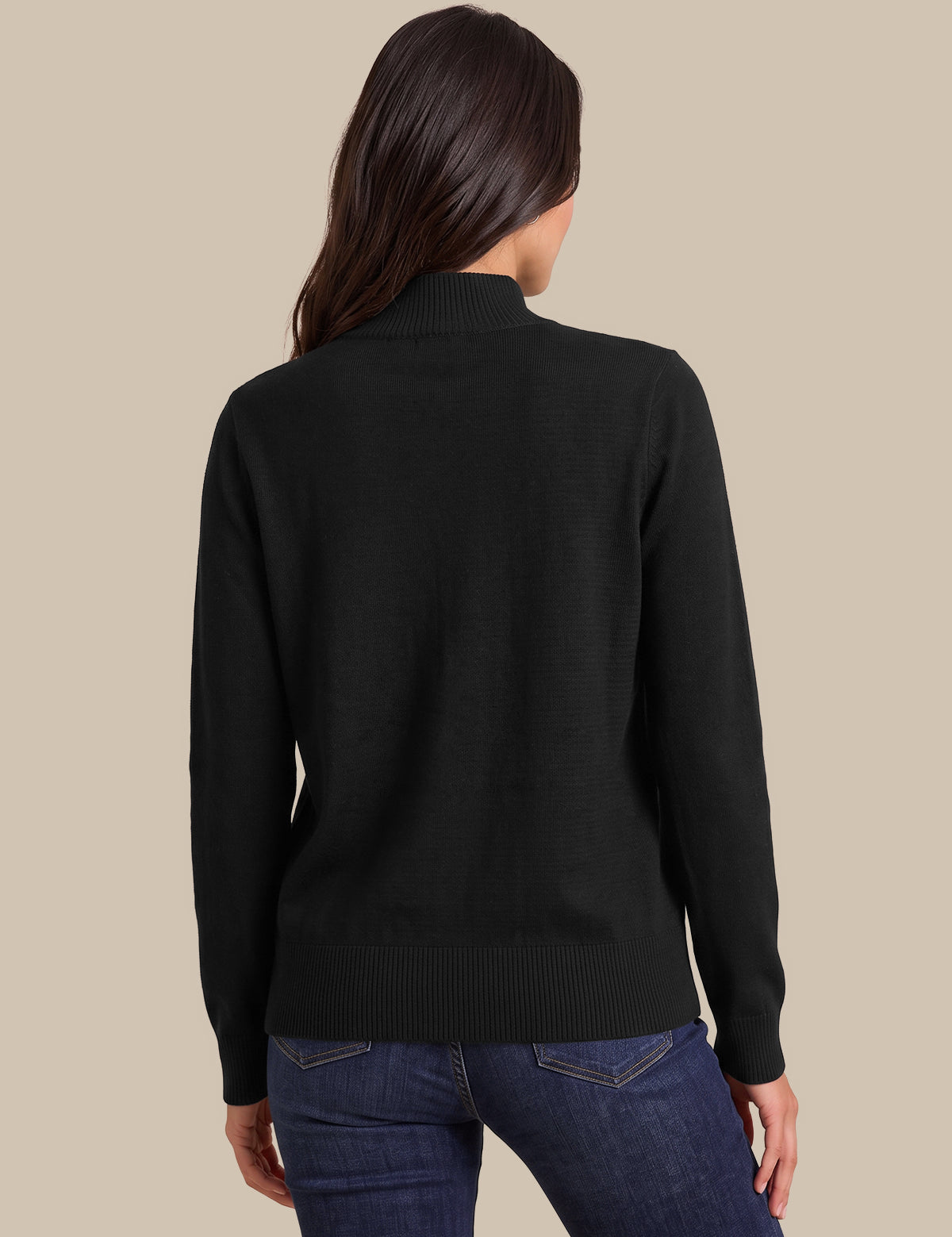 A woman shown from the back wearing a black mock neck knit sweater and blue jeans against a solid beige background.