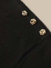 Close-up of a black ribbed knit sweater with three decorative gold-tone knotted buttons on the shoulder.