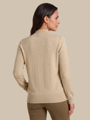 A woman shown from the back wearing a light beige knit sweater with a mock neck and ribbed hem and cuffs, paired with brown pants, against a solid beige background.