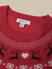 Close-up of a red knit sweater with a white and black holiday pattern featuring reindeer, a white heart, and snowflakes, with a visible 89FIRE MADSON neck label.