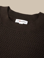 Close-up of a dark brown textured knit crewneck sweater with a white neck label reading '85% MADSON'.