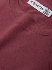 Close-up of a maroon garment with a label on a white background