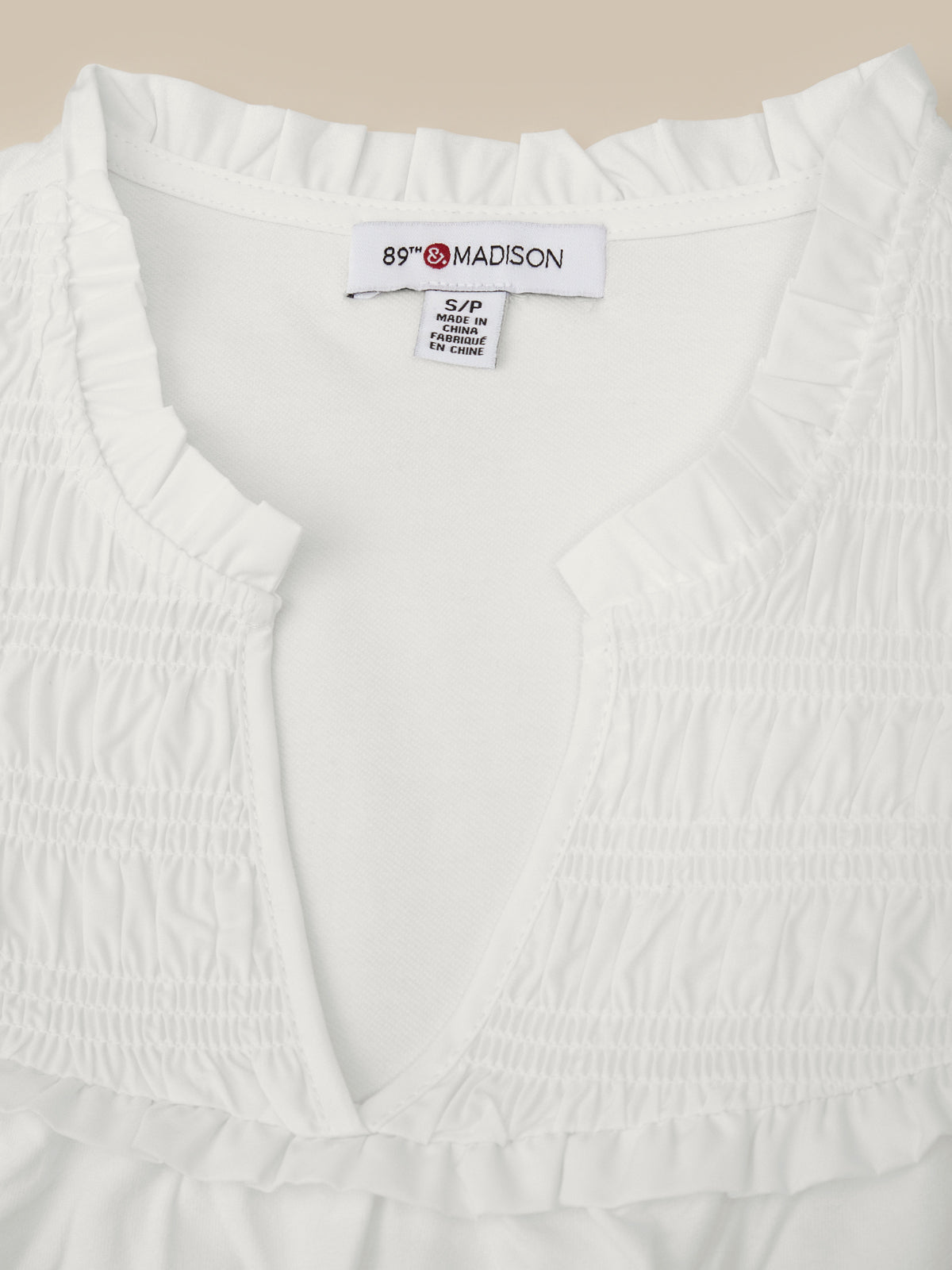 White garment with a visible brand label on a beige background