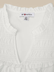 White garment with a visible brand label on a beige background