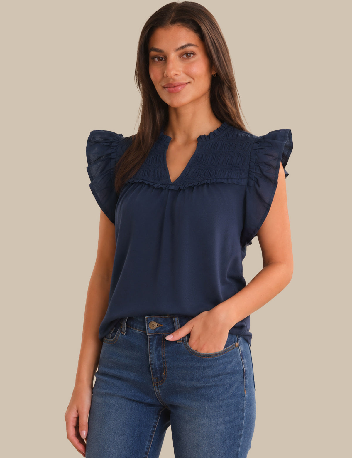 Woman wearing a navy blue top with ruffled sleeves against a beige background