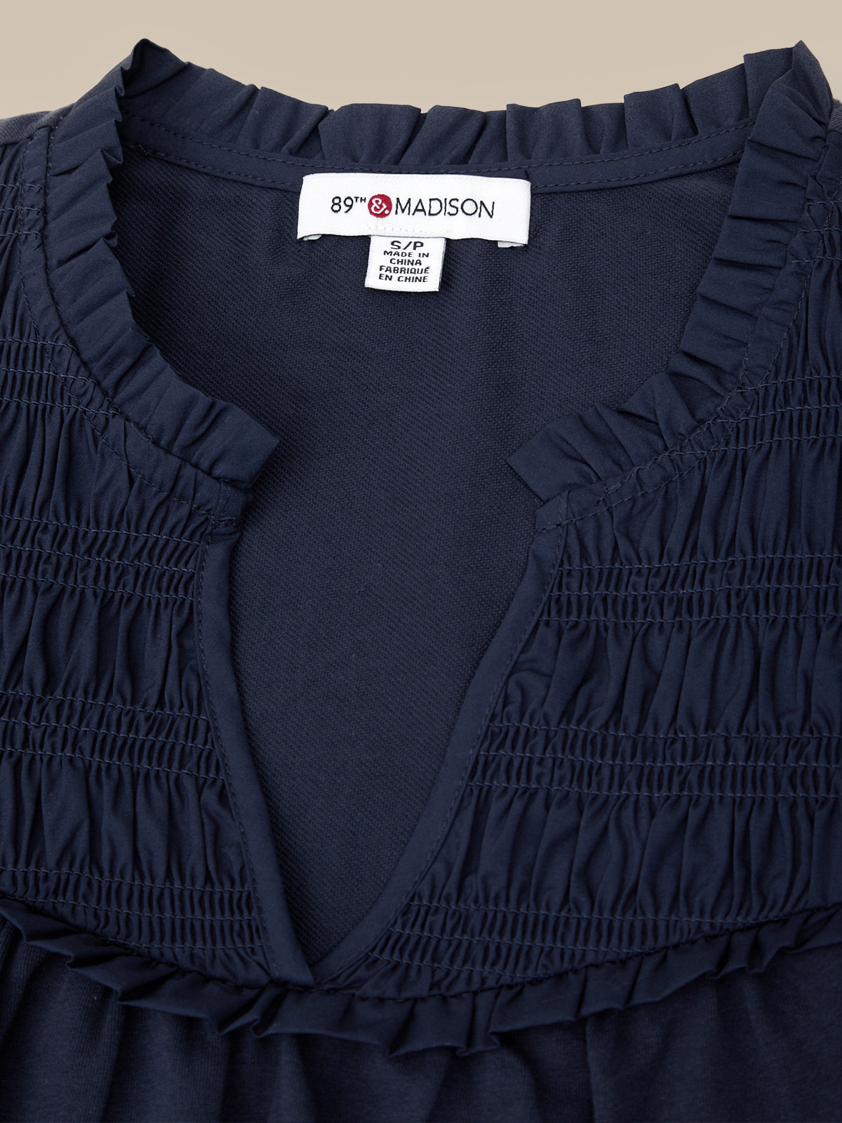 Navy blue dress with ruffled details and a visible brand label on a beige background
