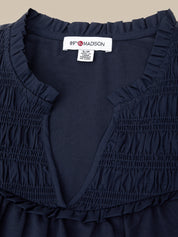 Navy blue dress with ruffled details and a visible brand label on a beige background