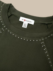 Close-up of a dark olive green top with silver stud embellishments around the neckline and shoulder, featuring a visible '69 MADISON' neck label.