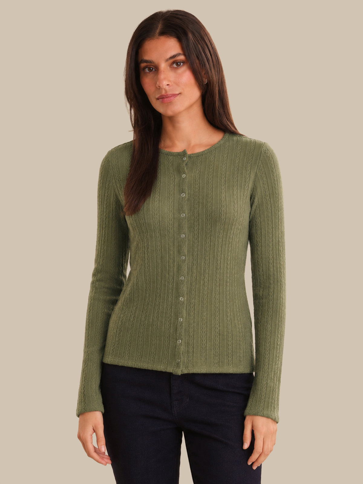Woman wearing a green ribbed cardigan against a beige background