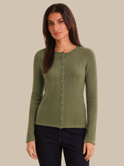 Woman wearing a green ribbed cardigan against a beige background
