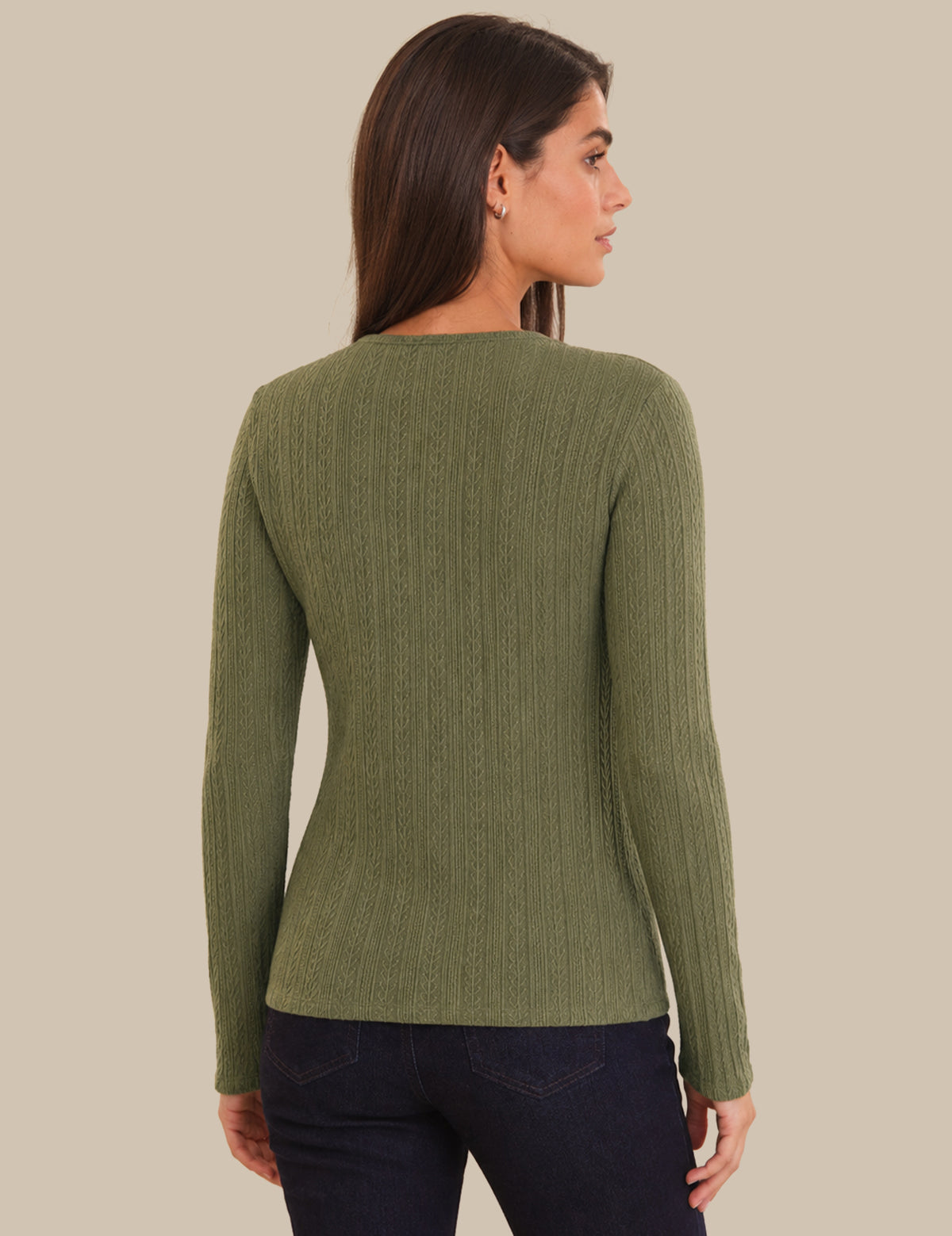 Woman wearing a green ribbed  cardigan against a beige background