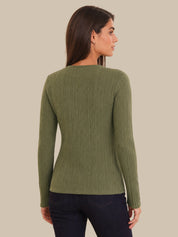 Woman wearing a green ribbed  cardigan against a beige background