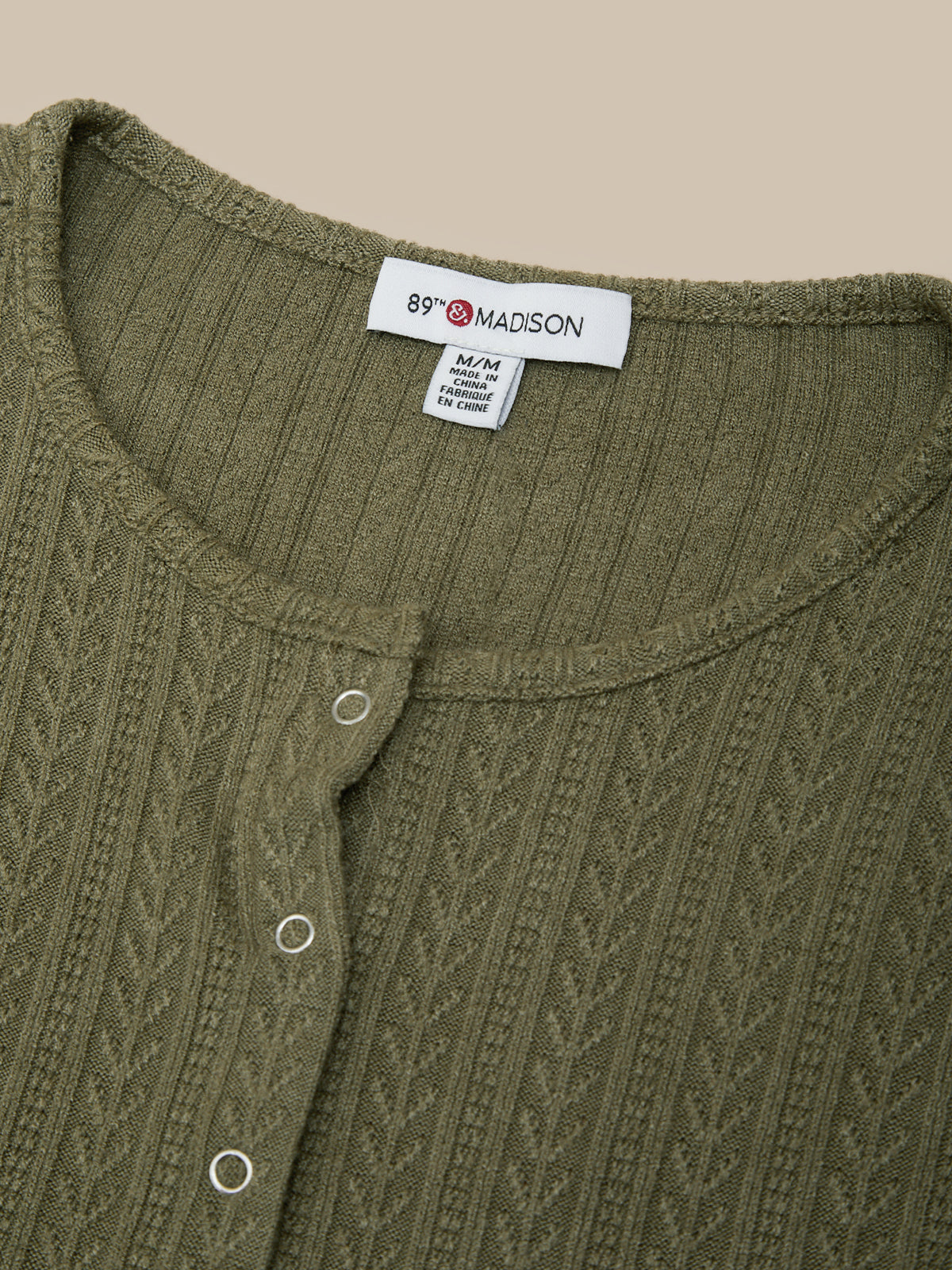 Close-up of a green knitted garment with a label on a beige background