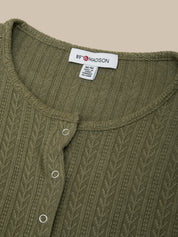 Close-up of a green knitted garment with a label on a beige background
