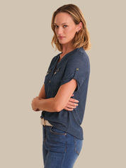 Woman wearing a blue shirt and jeans against a beige background