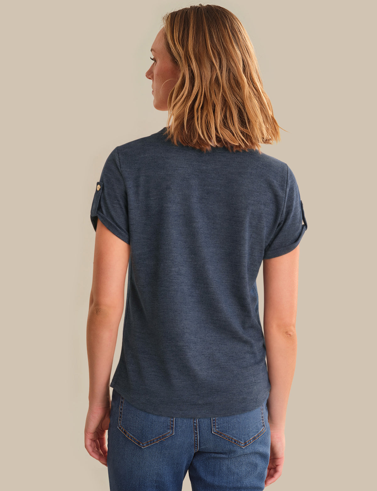 Woman wearing a blue t-shirt and jeans on a beige background