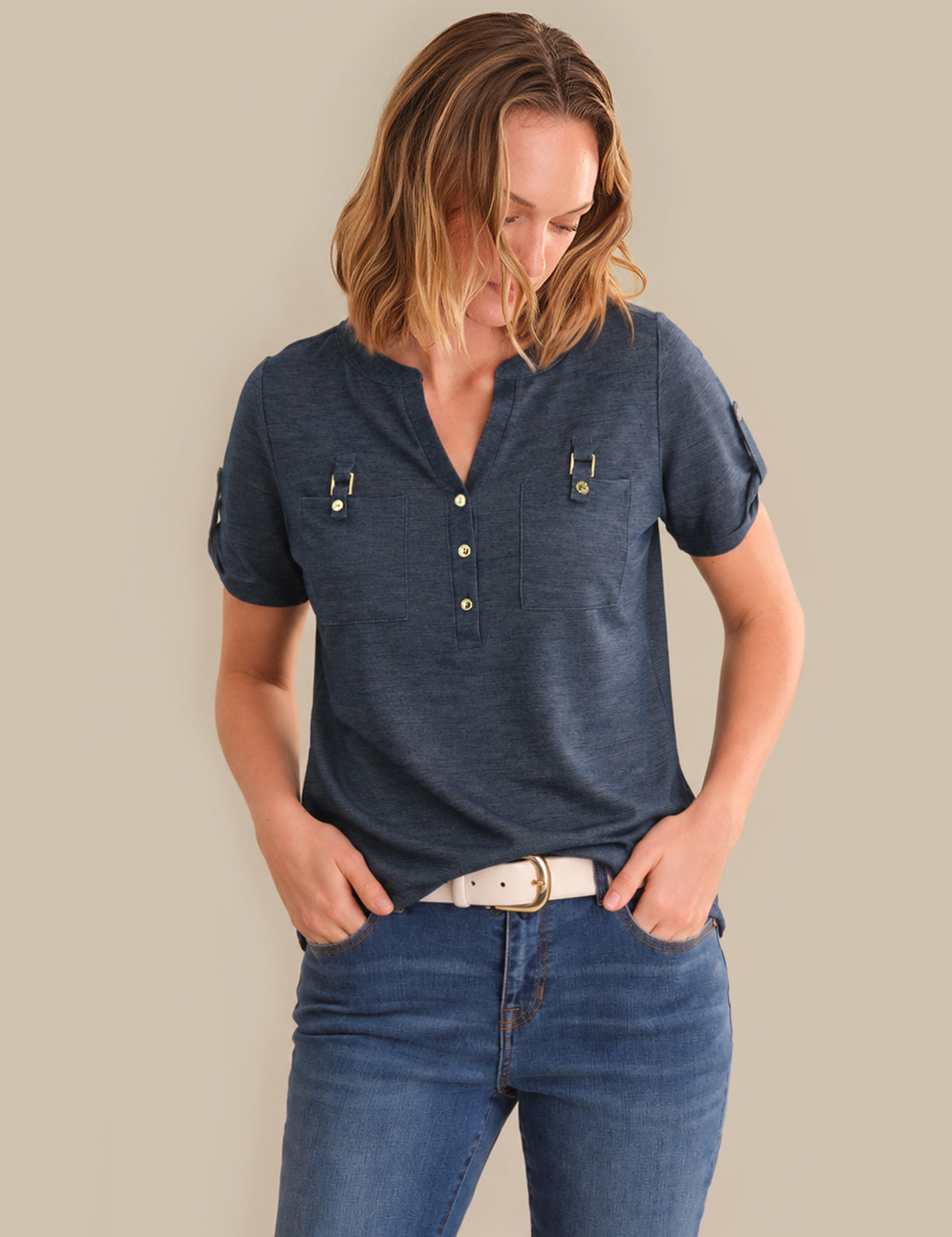 Woman wearing a blue shirt and jeans against a beige background