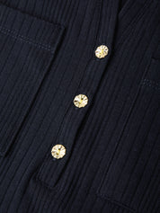Close-up of a dark navy ribbed fabric garment with three round gold-tone decorative buttons on the front.