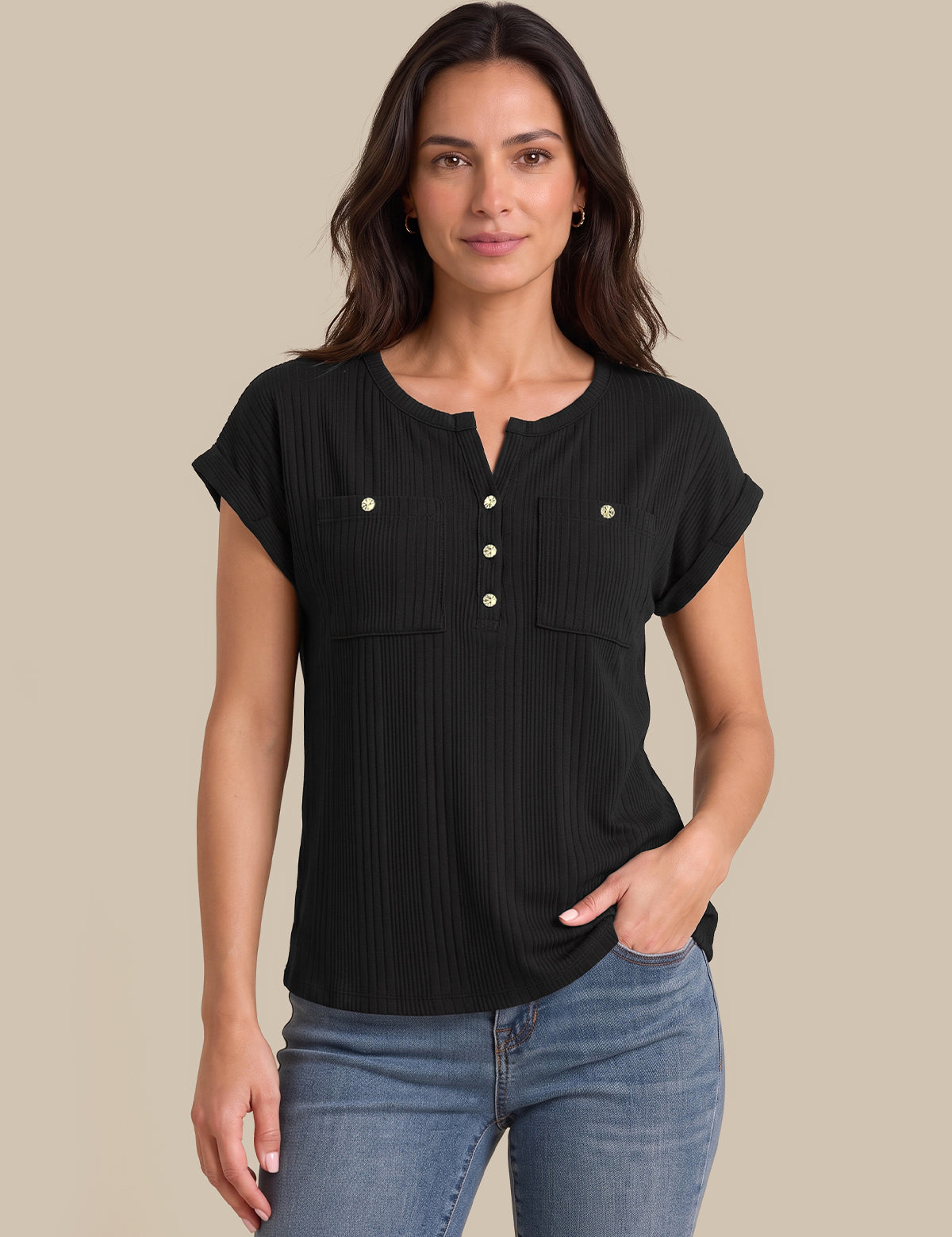 A woman modeling a black short-sleeve ribbed henley top with button details and chest pockets, paired with blue jeans, against a solid beige background.