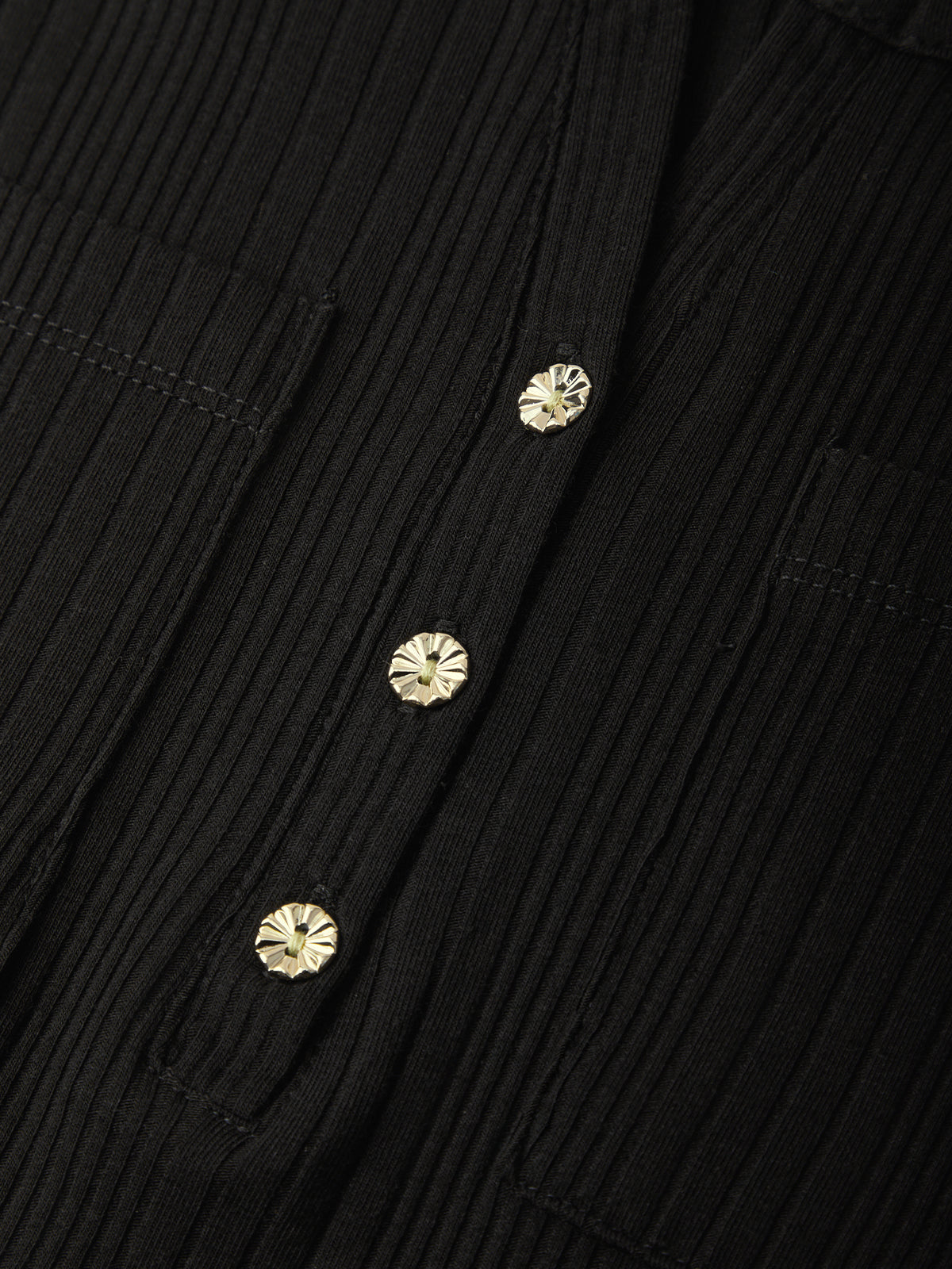 Close-up of a black ribbed button-up shirt featuring three decorative gold-toned floral buttons.