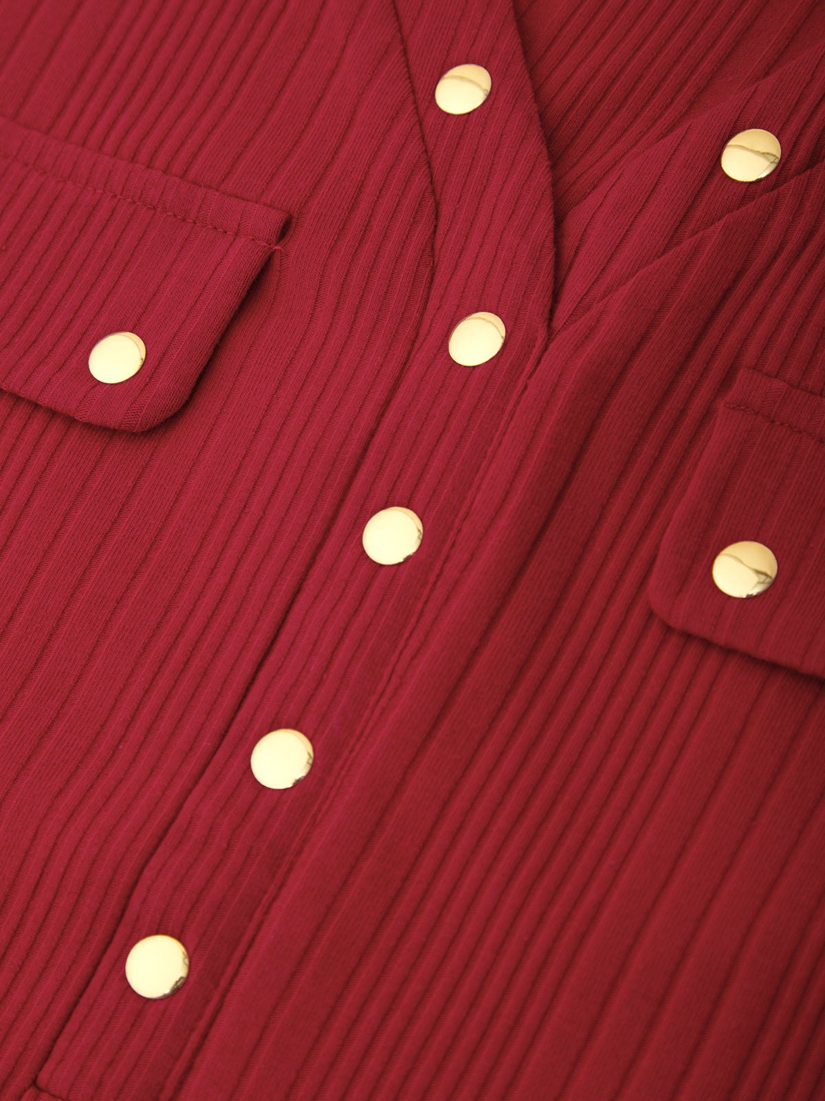 Close-up of a red ribbed corduroy garment with gold-tone snap buttons and flap pockets.