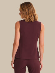 Woman wearing a maroon sleeveless top and pants against a beige background