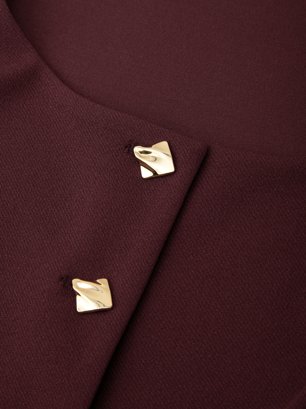 Close-up of a burgundy fabric with gold buttons