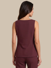 A woman shown from the back wearing a sleeveless, structured peplum-style top and matching pants in a deep burgundy or maroon color, set against a solid beige studio background.
