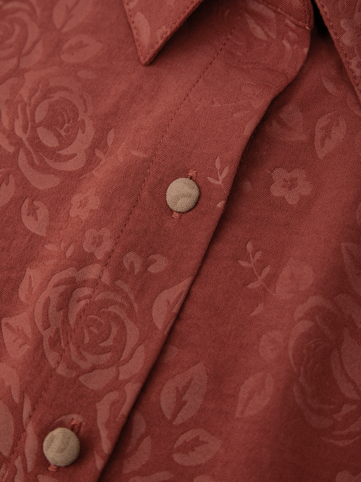 Close-up of a red floral patterned shirt with buttons.