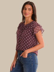 Woman wearing a patterned top and jeans on a beige background