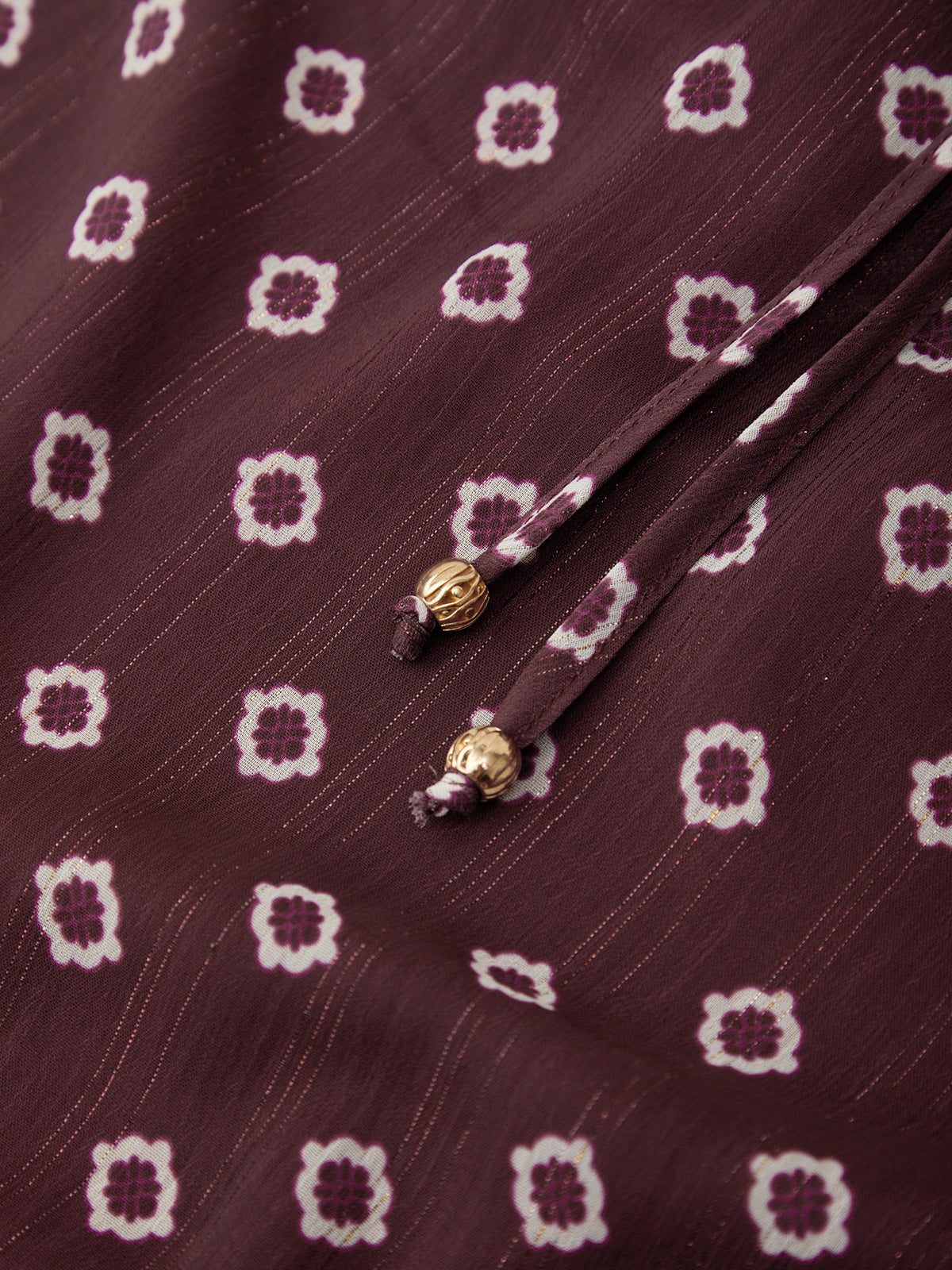 Close-up of a fabric with a pattern and decorative elements on a maroon background