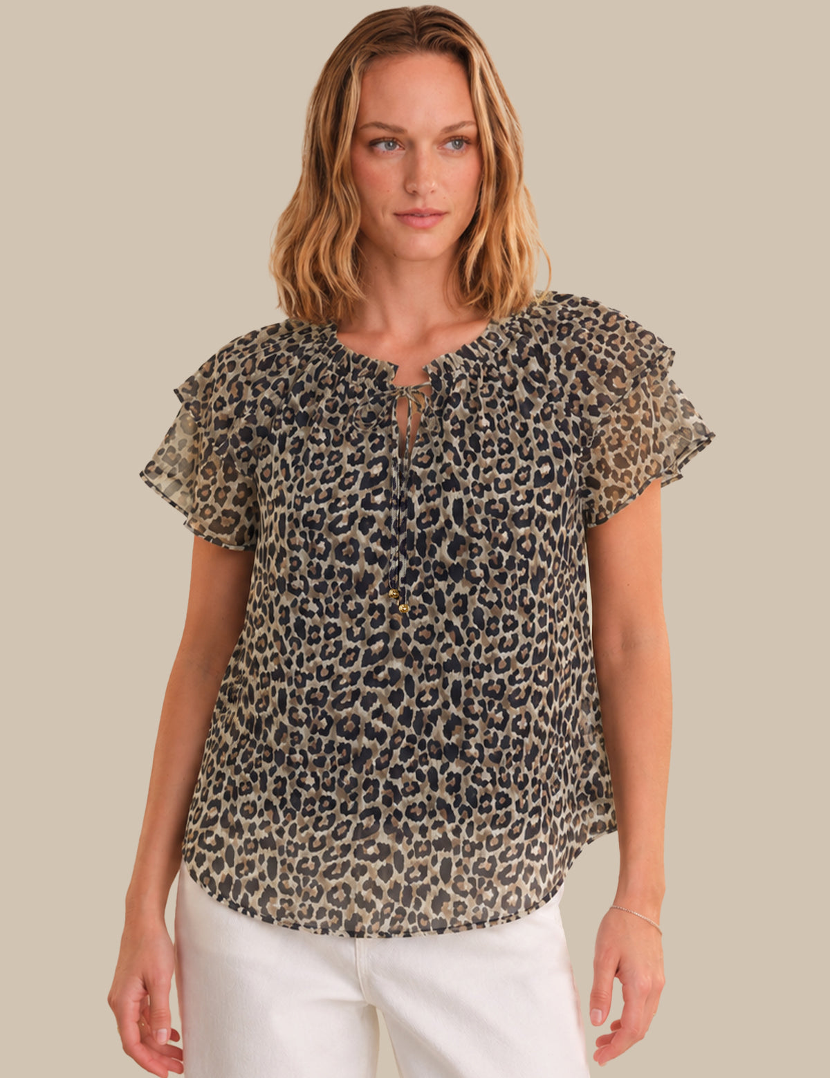 Woman wearing a leopard print blouse with ruffled sleeves on a beige background