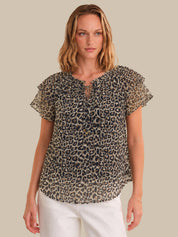 Woman wearing a leopard print blouse with ruffled sleeves on a beige background