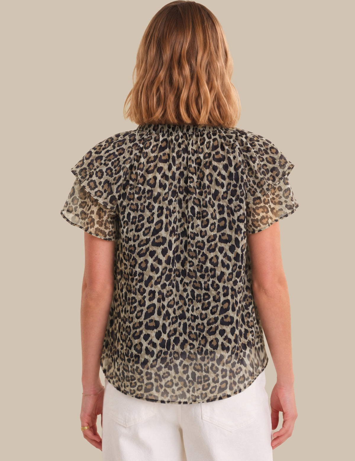 Woman wearing a leopard print blouse with ruffled sleeves on a beige background